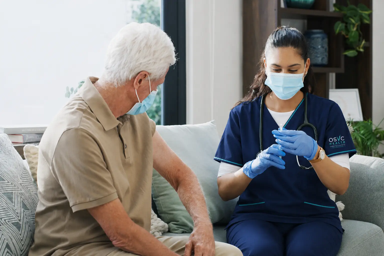 nurse sitting on couch giving a vaccine